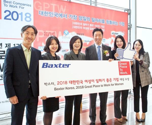 Baxter employees standing with great place to work for woman banner